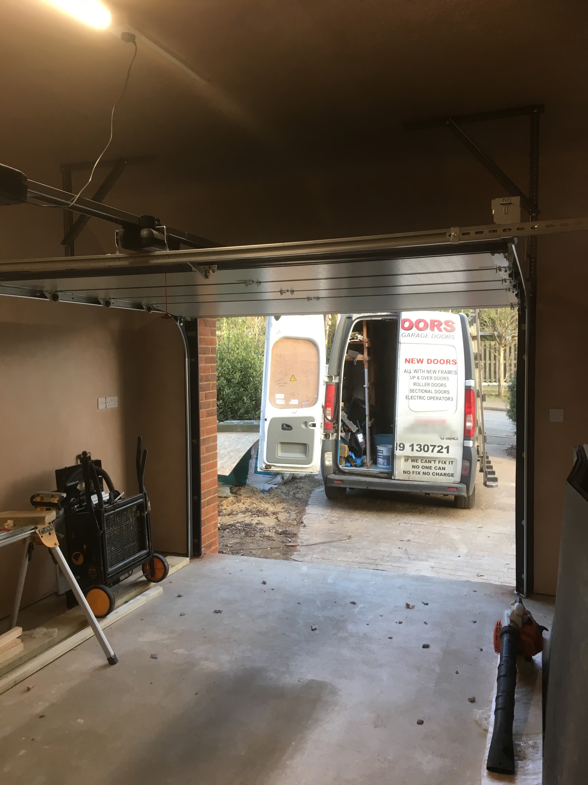 The Alldoors van parked outside a garage with a new sectional door raised, seen from inside the garage