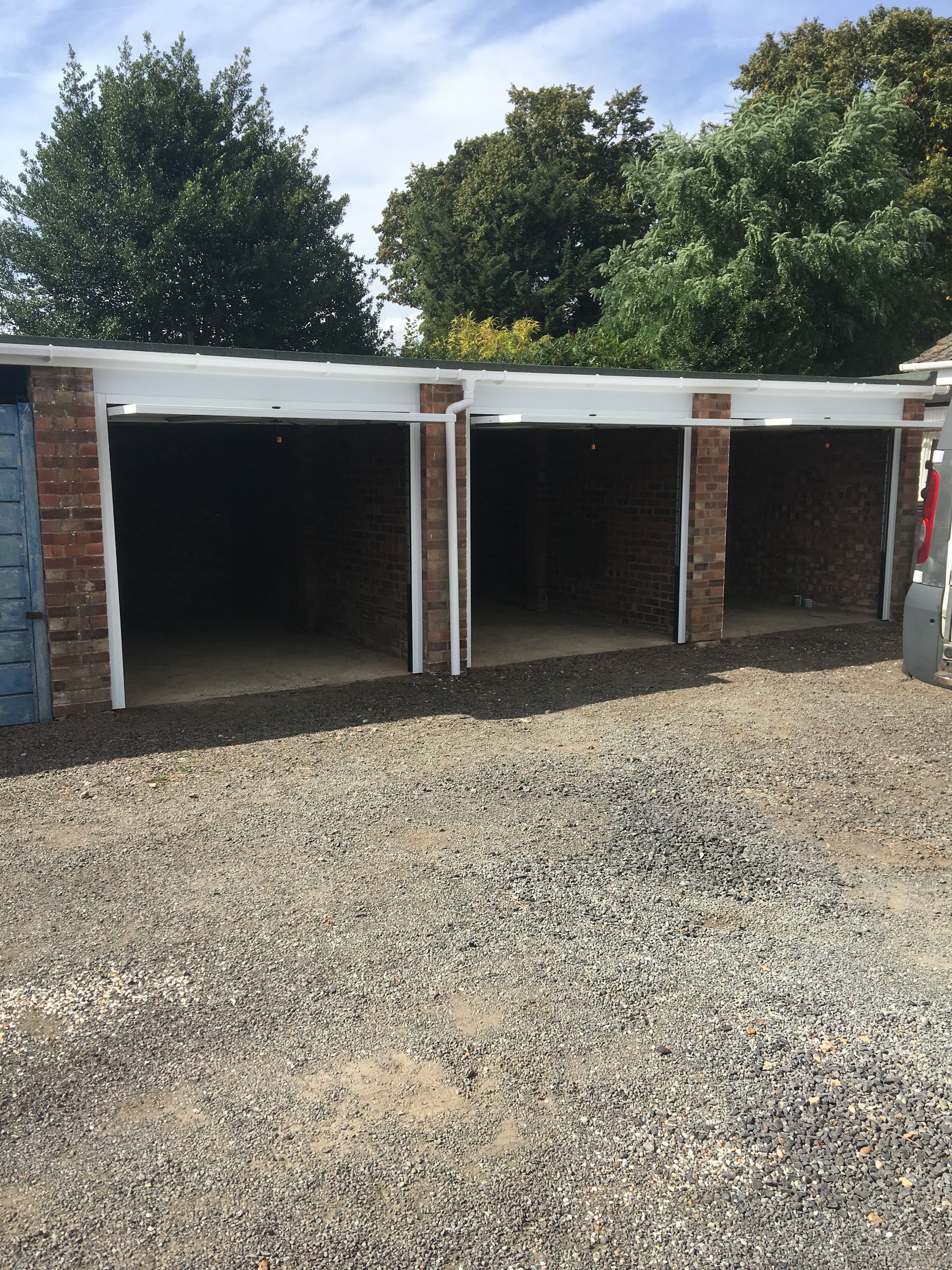 A row of three garage openings with new white frames fitted, ready for the doors