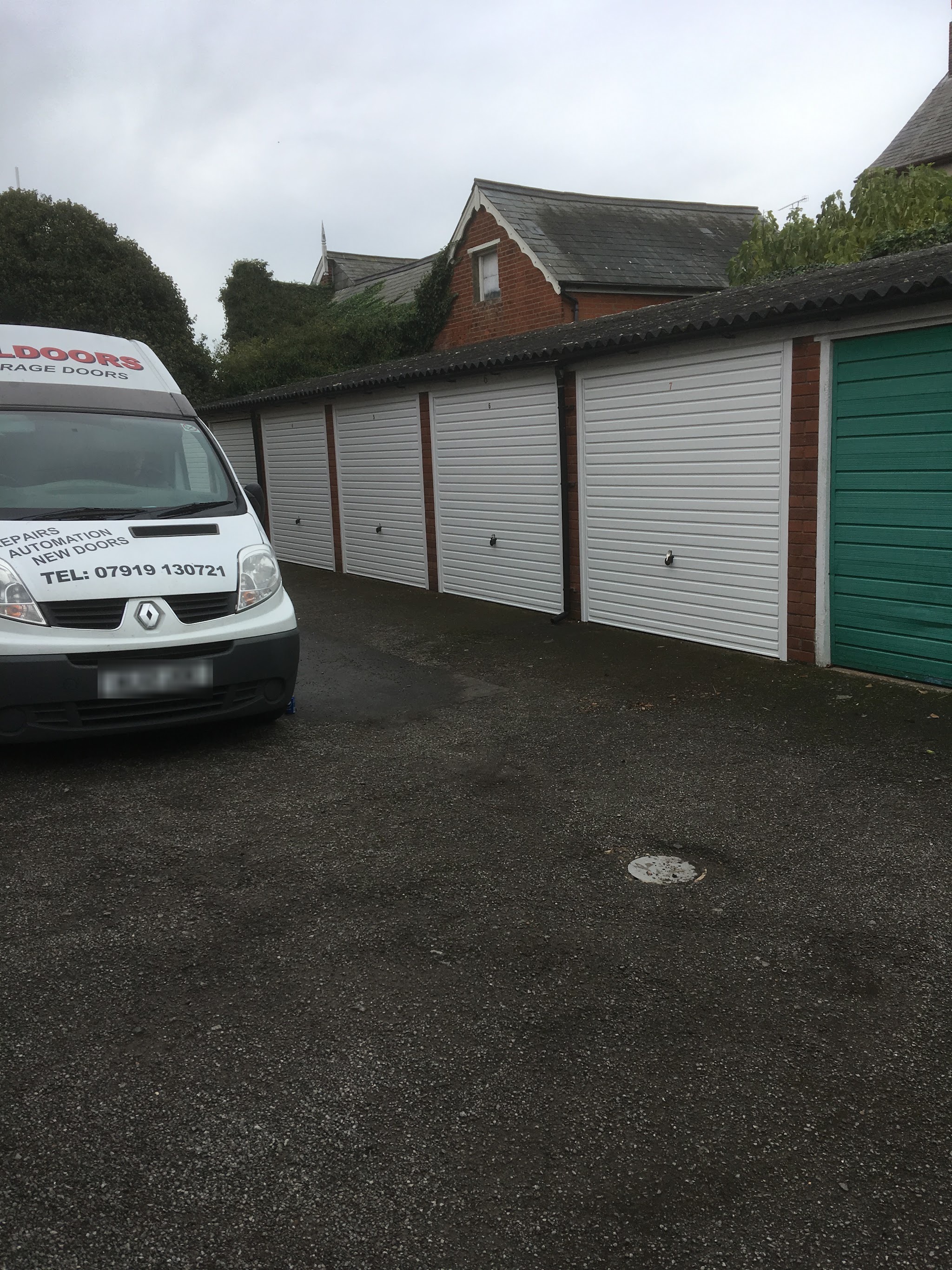 The white Alldoors van, lettered Repairs, Automation, New doors and the phone number, beside a row of new white up and over doors on lock-up garages