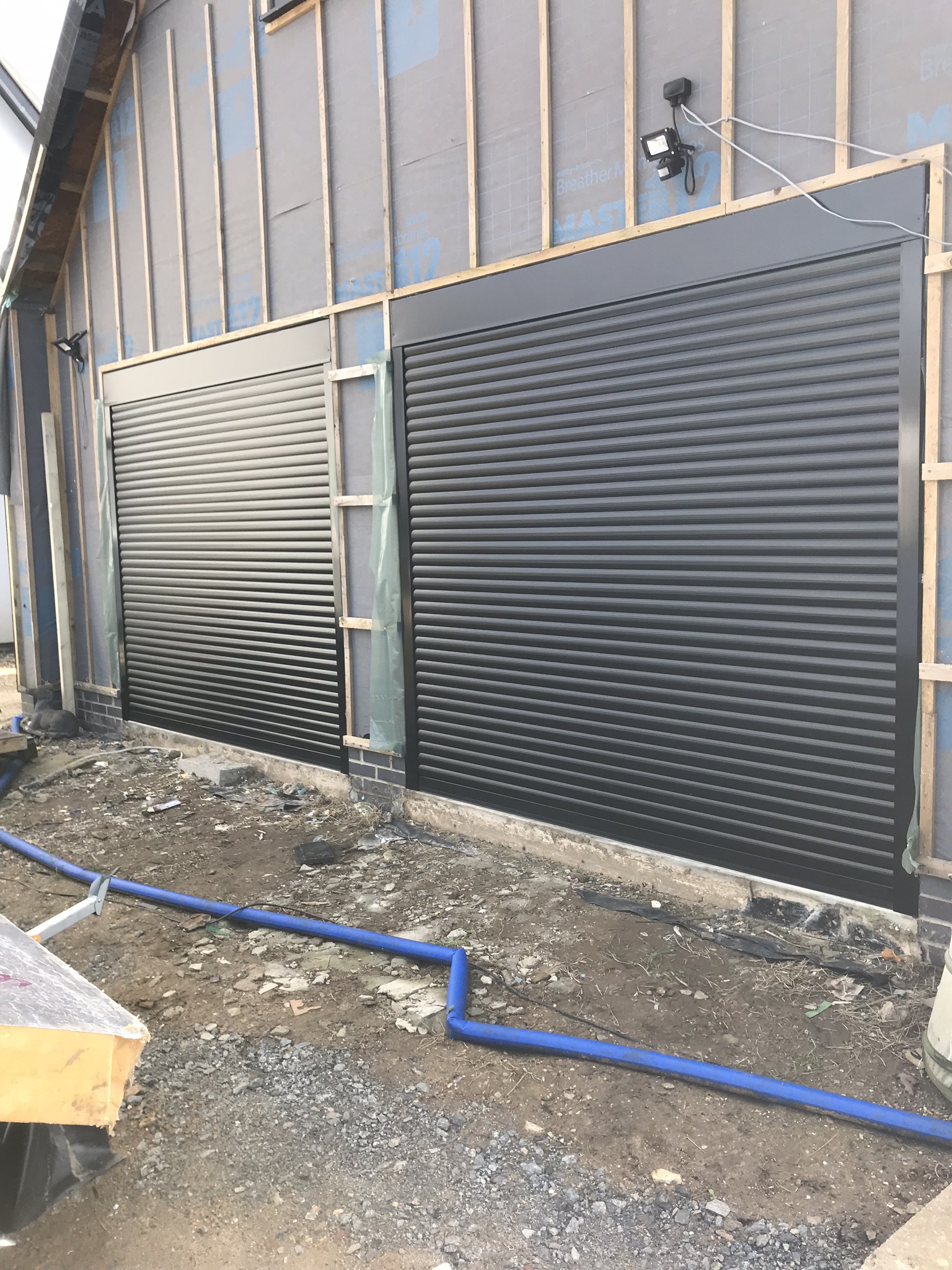Two anthracite roller doors fitted to a new timber-clad garage