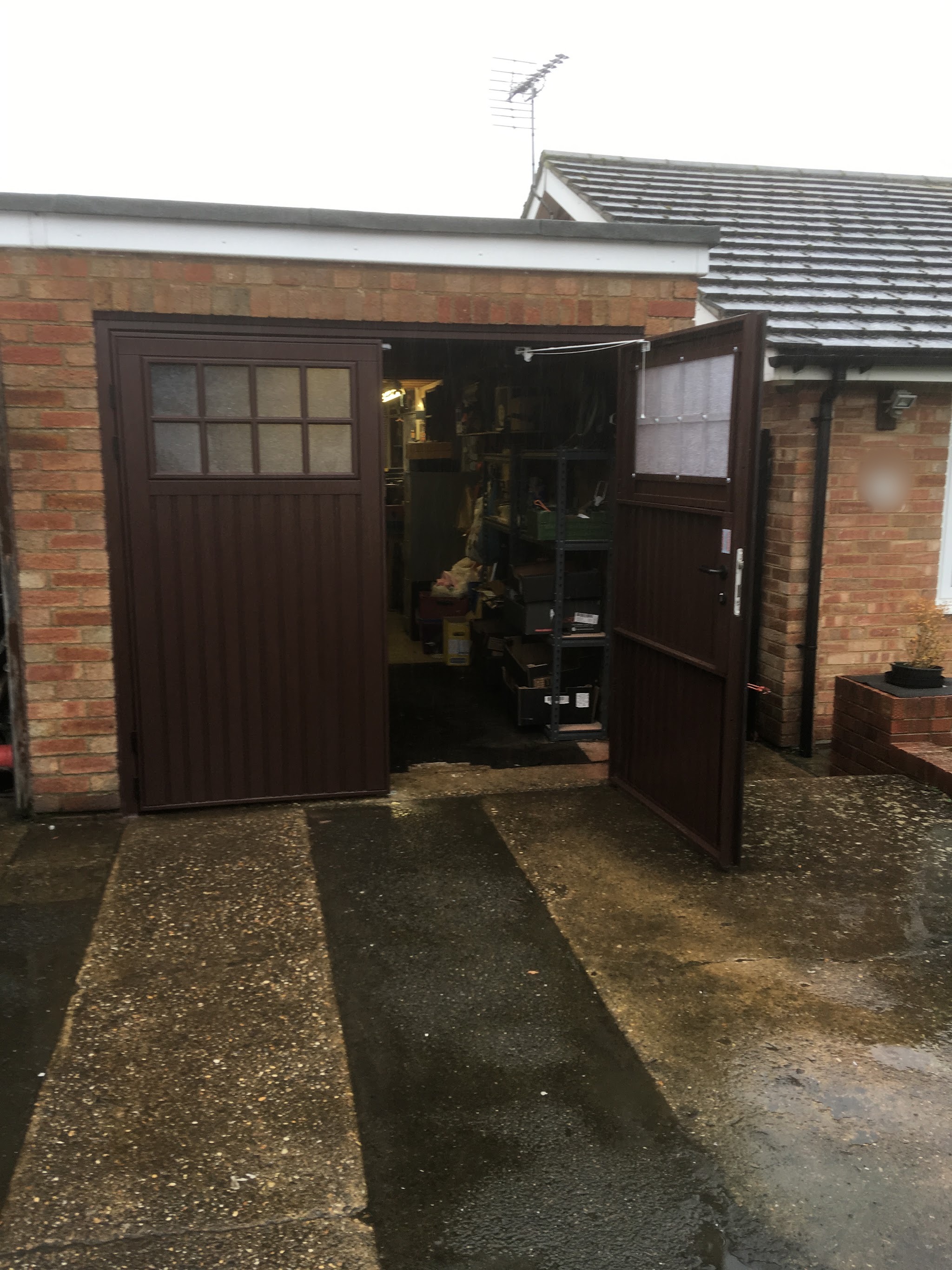 Brown side-hinged garage doors with glazed top panels standing open